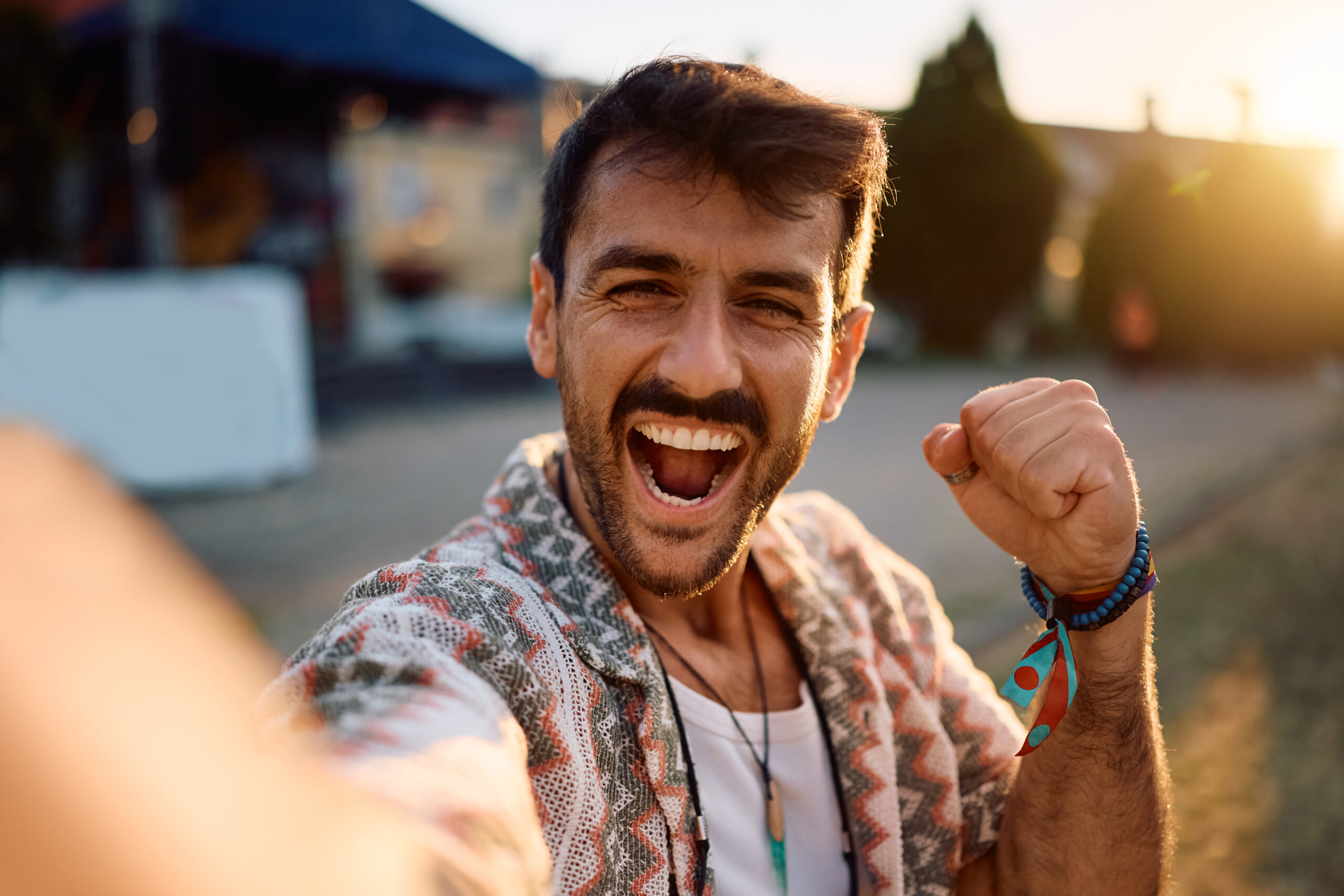 Cheerful man taking selfie during summer music festival and looking at camera.